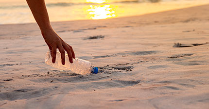 hand picking up bottle off beach